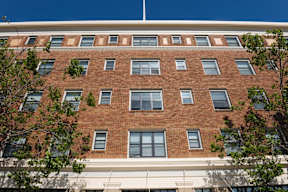 A red brick building with a white trim around the windows and a white awning below the windows.