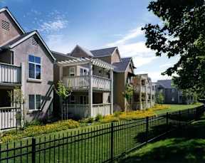 A row of houses with a black fence in front.