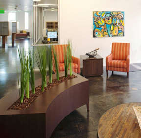A modern office lobby with orange chairs and a wooden planter.