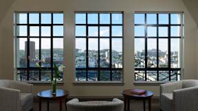 A room with a table and chairs and a view of the city through the windows.