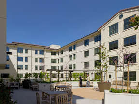 A courtyard with tables and chairs surrounded by buildings.