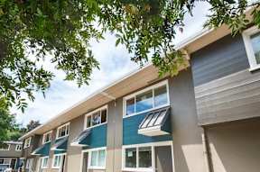 A row of modern apartment buildings with balconies and trees in the foreground.