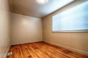 A room with wooden floors and a window with blinds.