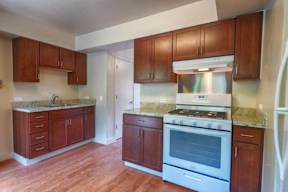 A kitchen with wooden cabinets and a white stove top oven.