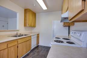 A kitchen with wooden cabinets and a white stove top oven.