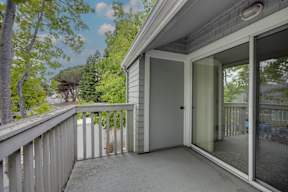 A balcony with a glass door leading to a deck.