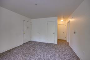 A room with carpeted floor and white walls with three doors.