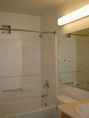 A white bathroom with a toilet, sink, and shower.