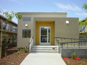 A modern building with a yellow door and a concrete staircase leading to it.