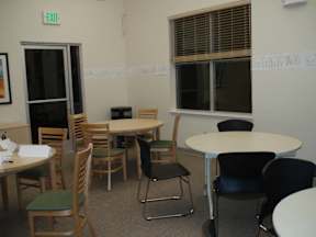A room with tables and chairs and an exit sign.
