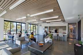 A group of people are sitting and standing in a modern open plan office space.