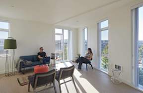Two people sitting on chairs in a room with large windows.