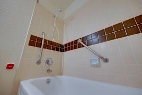 A white bathtub with a shower head and hand held shower.