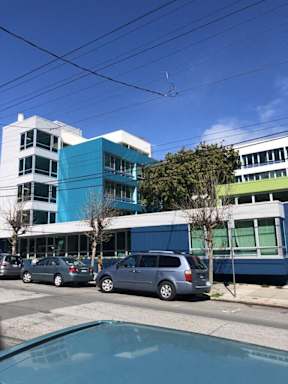 A blue and white building with cars parked in front.