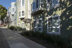 A row of houses with a sidewalk in front.