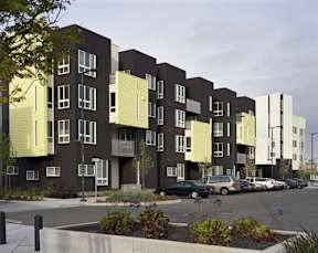 A modern apartment complex with cars parked in the driveway.