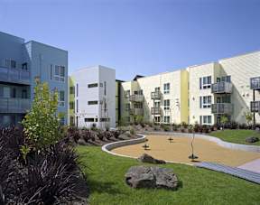 A playground area in front of a row of modern buildings.