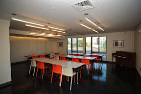 A room with tables and chairs and a piano.