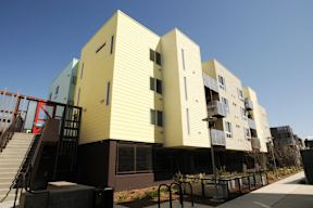A modern building with a yellow facade and a staircase leading to the entrance.