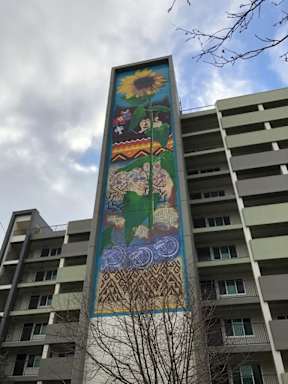 A large mural on a building with a sunflower at the top.