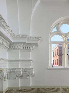 A white staircase with a window showing a building outside.