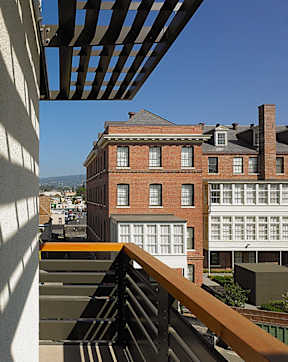 A view from a balcony looking down at a building with a red brick facade.