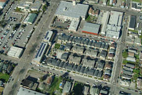 A bird's eye view of a city street with buildings, cars, and trees.