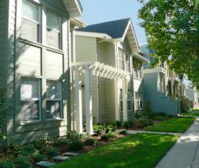 A row of houses with a white picket fence in front.
