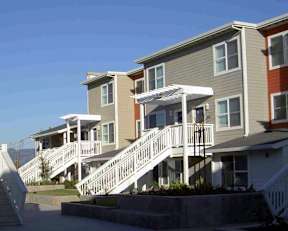A row of houses with white railings and stairs leading to the doors.