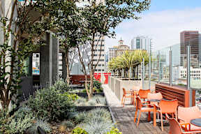 A rooftop patio with orange chairs and tables.