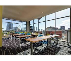 A room with tables and chairs and a view of the city outside the windows.