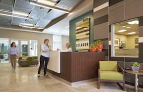 A reception area with a woman standing at the desk.