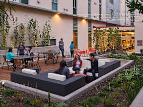People are sitting and standing on a patio.