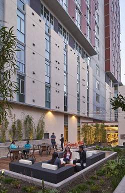 People are sitting and standing on a patio outside a building.