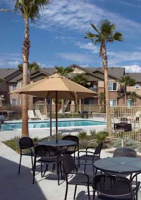A patio with a table, chairs, and an umbrella is set up next to a pool.