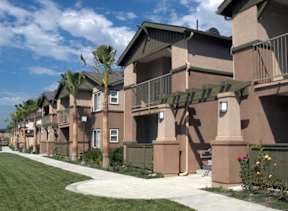 A row of houses with a green lawn in front.