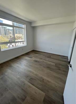 A room with wooden flooring and a large window.