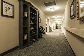 A long hallway with a bookcase on the left and a mirror on the right.