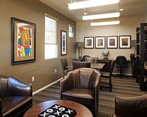 A room with brown leather chairs and a framed painting on the wall.
