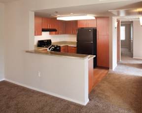 A kitchen with brown cabinets and a black fridge.