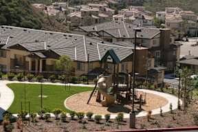 A playground with a slide and a green roofed building in the background.