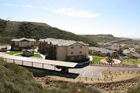 A bridge over a parking lot with a hill in the background.