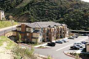 Apartment complex with a parking lot in front.