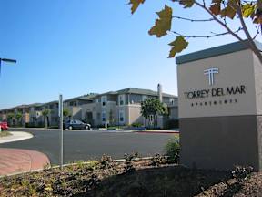 A sign for Torrey Del Mar Apartments stands in front of apartment buildings.
