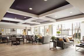 A modern living room with a grey couch and a dining table.