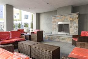 A patio with a stone fireplace and wicker furniture.