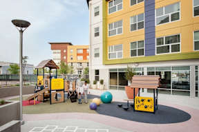 A playground with a slide, swings, and a ball.