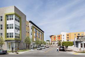 A street view of a residential area with cars and buildings.