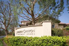 A sign for Augusta Canyon Apartment Homes is in front of a house.