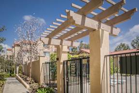 A wooden pergola is in the foreground of a residential area.